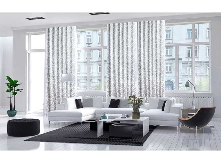 A black and white room showcasing long, white drapes over two large windows